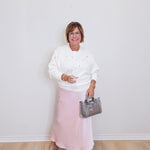 woman wearing a cream floral sweater against a white background. 