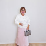 woman wearing a cream floral sweater against a white background. 