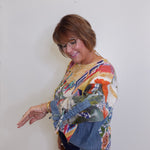 Woman wearing a colorful patterned sweater against a white wall