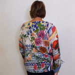 Person wearing a colorful floral-patterned sweater against a white wall