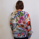 Person wearing a colorful floral-patterned sweater against a white wall