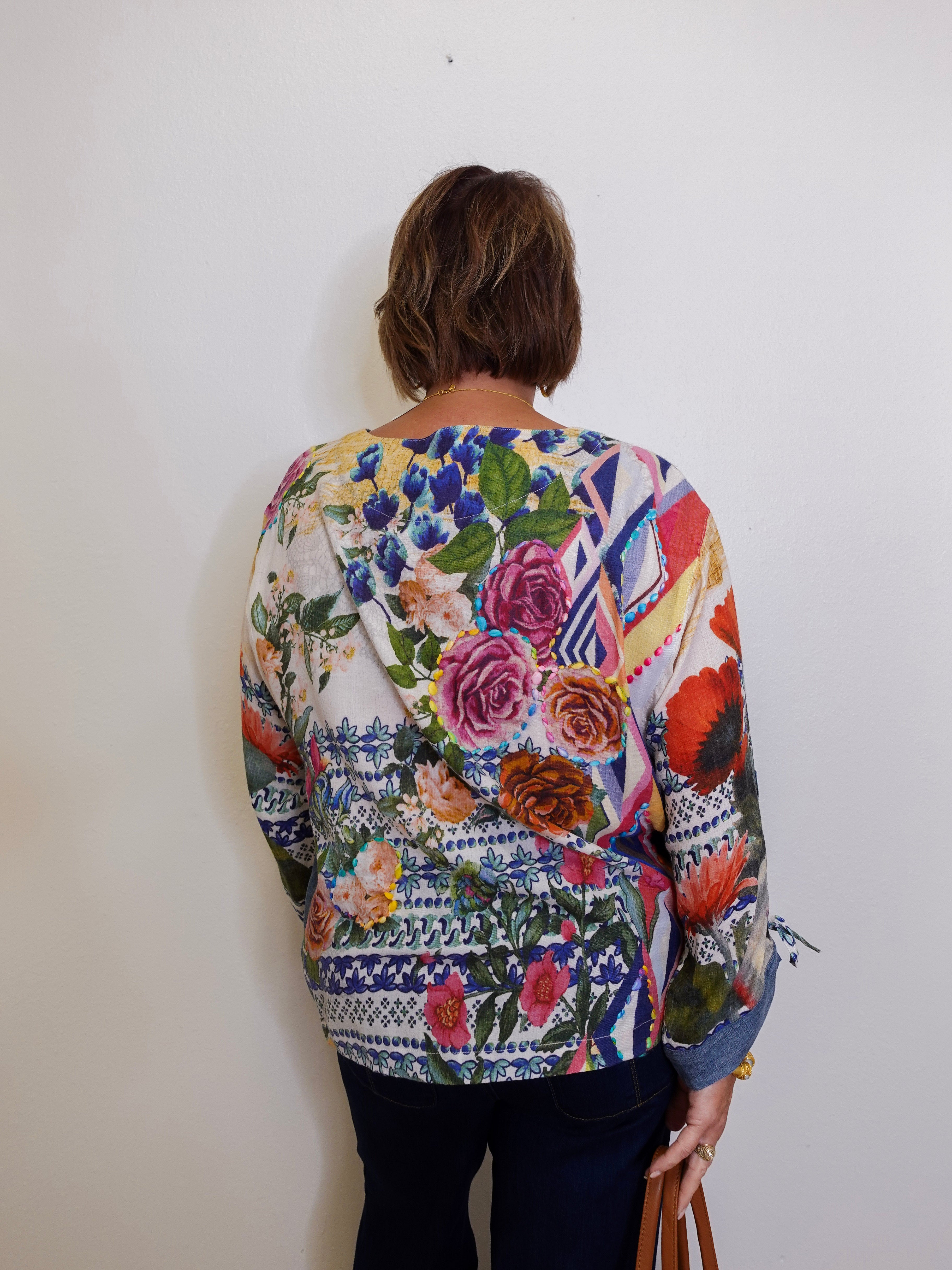 Person wearing a colorful floral-patterned sweater against a white wall