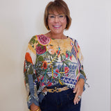 Woman wearing a colorful floral blouse and dark jeans against a white background