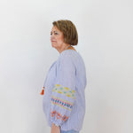 Woman wearing a light blue blouse with colorful embroidery on a white background