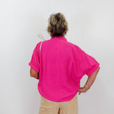 Person wearing a bright pink shirt and beige pants against a white background