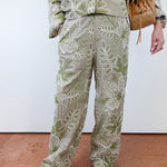 Person wearing a green and white floral outfit with a white background