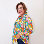Woman wearing a colorful patterned shirt against a white background