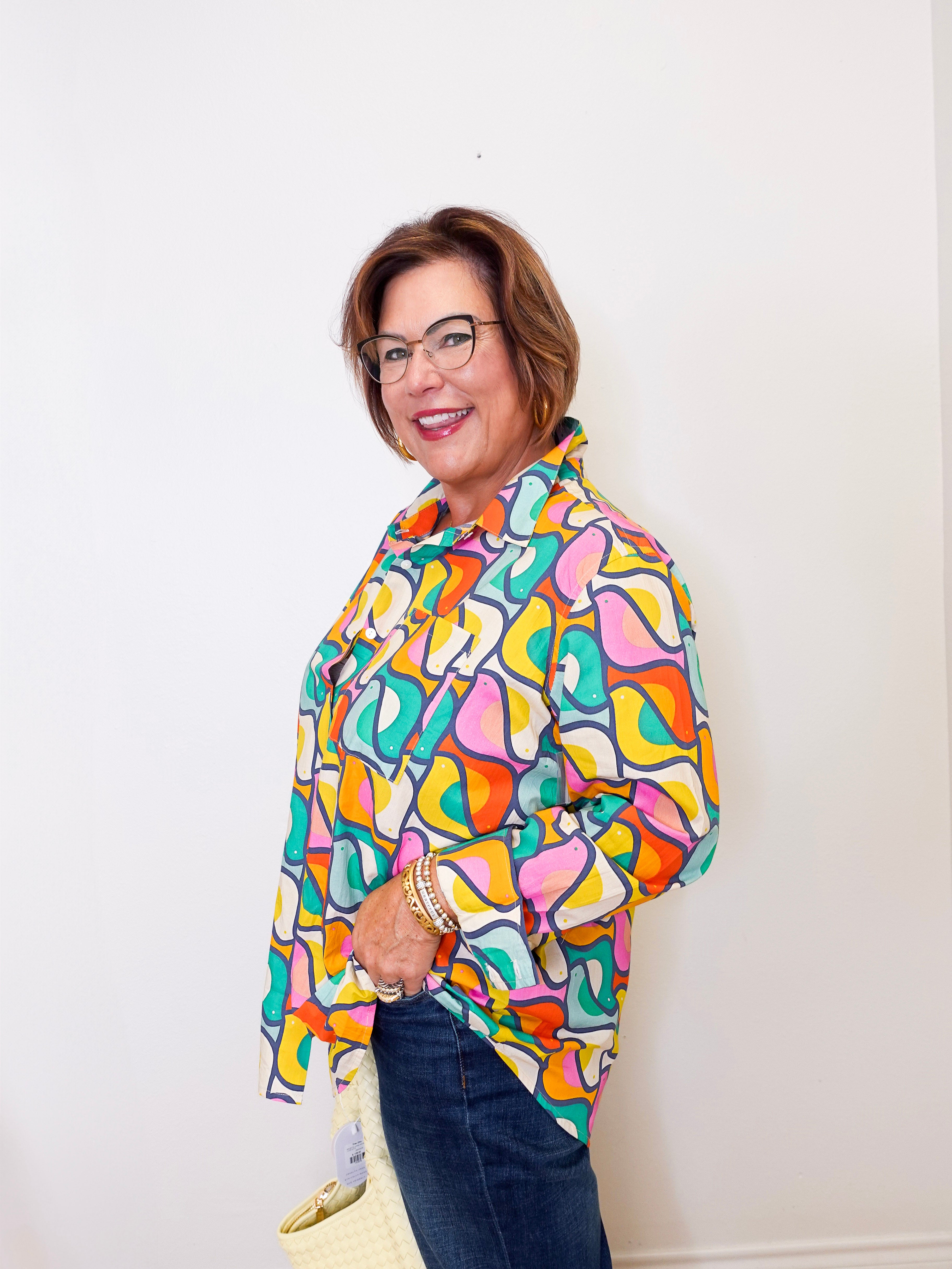 Woman wearing a colorful patterned shirt against a white background
