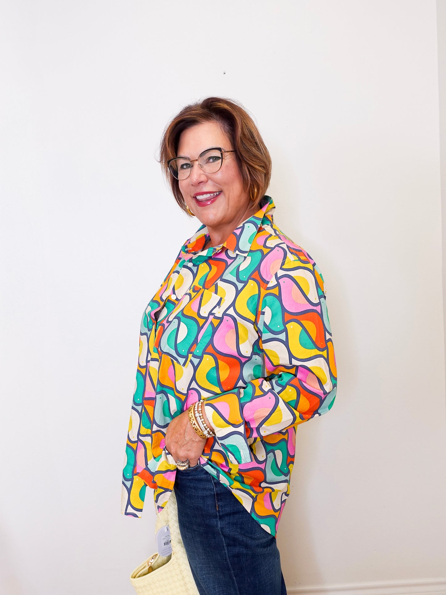 Woman wearing a colorful patterned shirt against a white background
