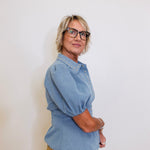 Person wearing a blue shirt and glasses against a white background