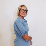 Person wearing a blue shirt and glasses against a white background
