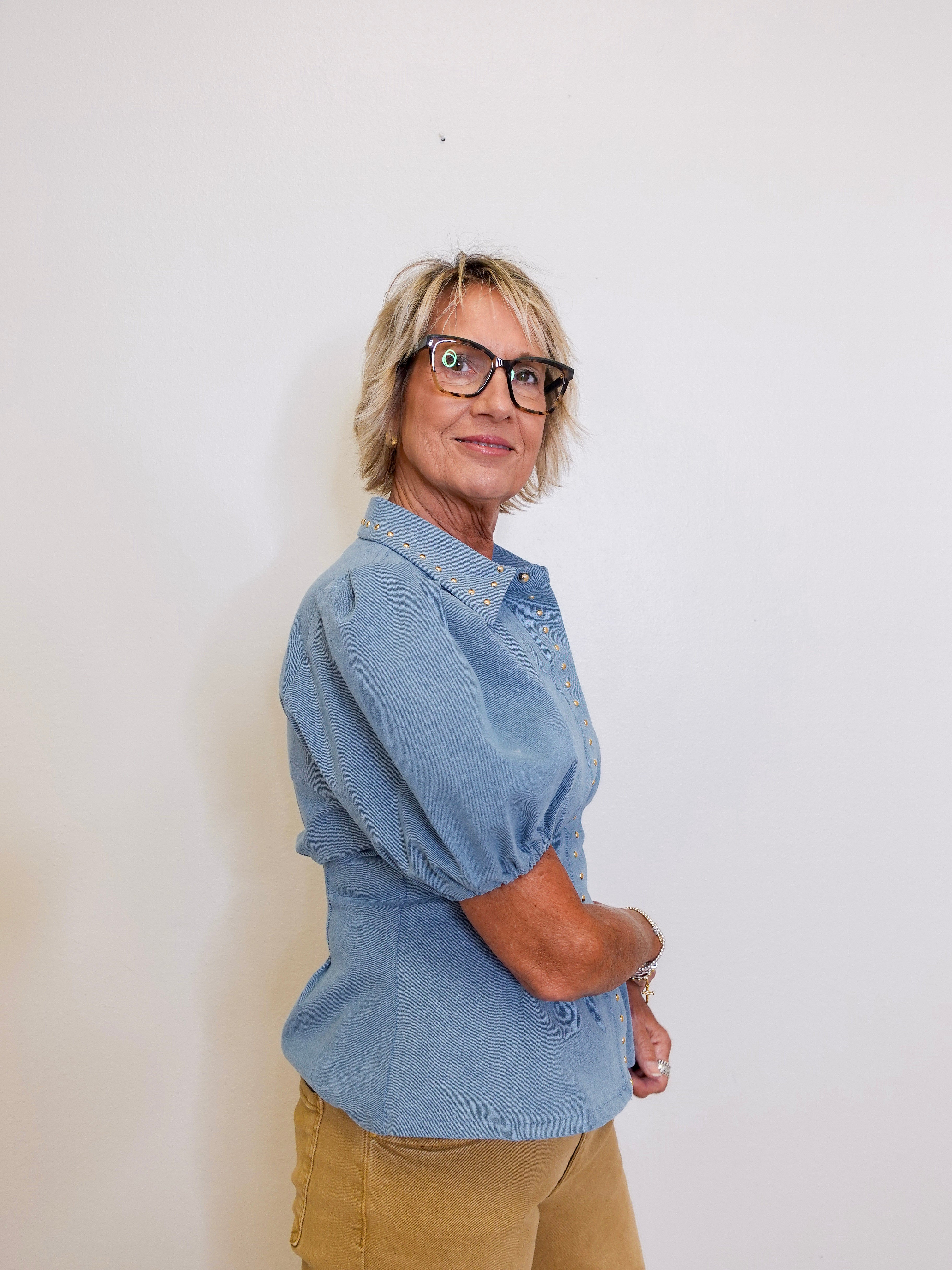 Person wearing a blue shirt and glasses against a white background