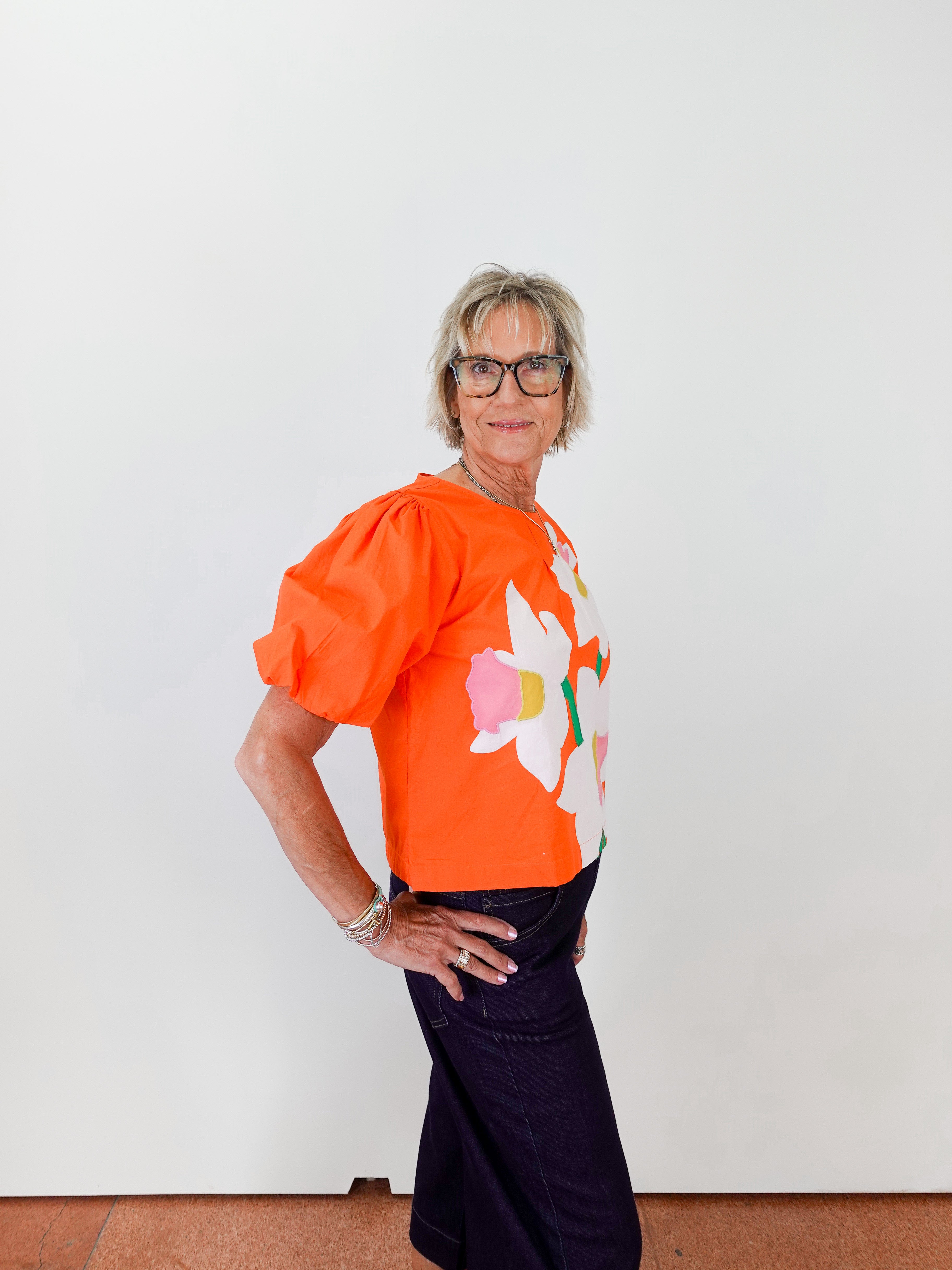 Person wearing an orange top with a floral design against a white background