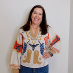 Woman wearing a colorful sweater with cowboy design against a plain background