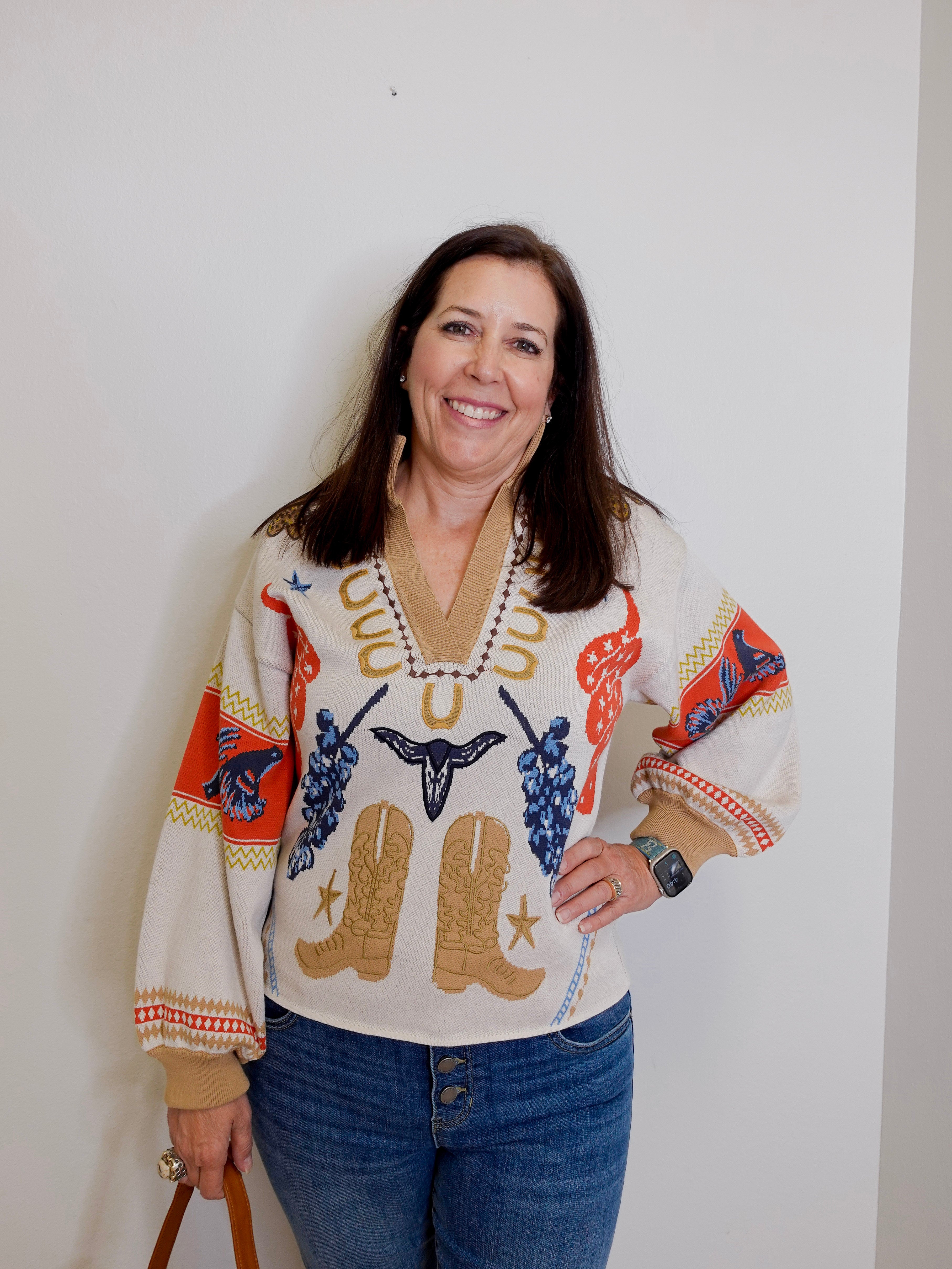 Woman wearing a colorful sweater with cowboy design against a plain background