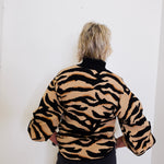 Person wearing a tiger-striped jacket against a white background