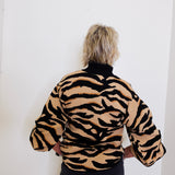 Person wearing a tiger-striped jacket against a white background