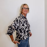 Woman wearing a black and white patterned blouse against a plain background