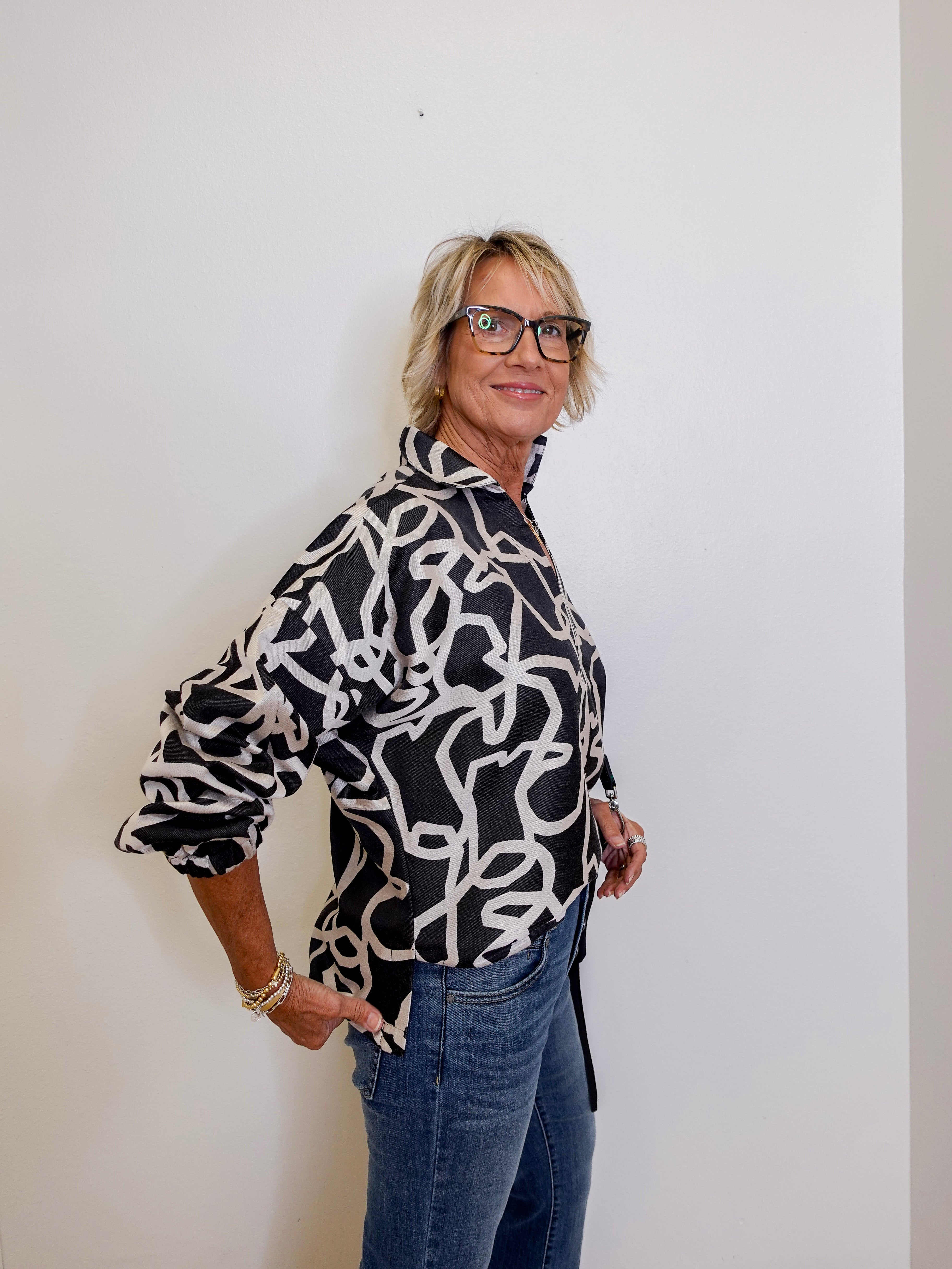 Woman wearing a black and white patterned blouse against a plain background