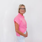 Woman wearing a pink shirt and glasses against a white background