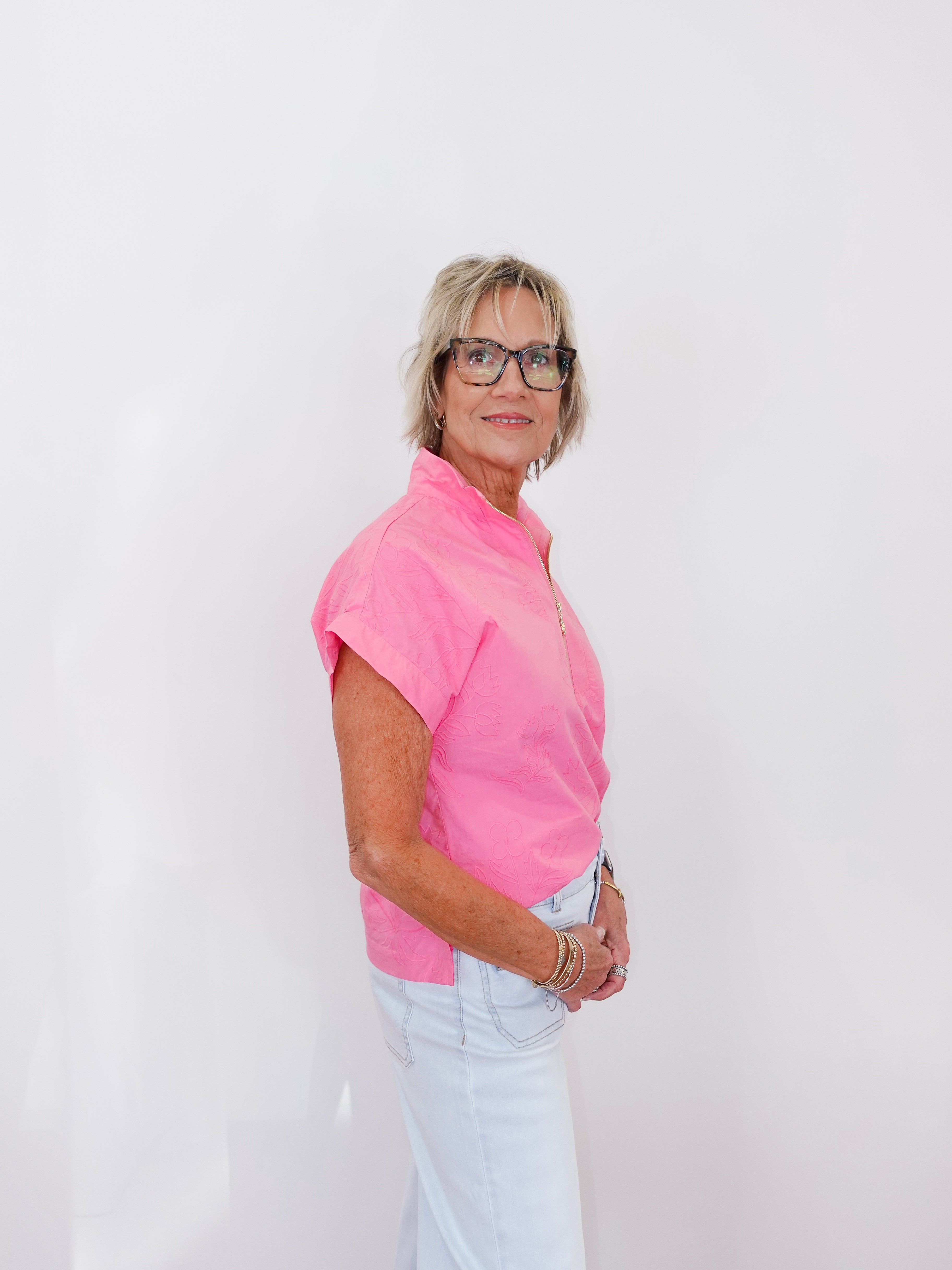 Woman wearing a pink shirt and glasses against a white background