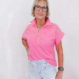 Woman wearing a pink short-sleeve top and light blue jeans against a white background