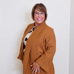 Woman wearing a brown cardigan over a patterned shirt against a white background