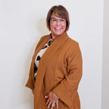 Woman wearing a brown cardigan over a patterned shirt against a white background