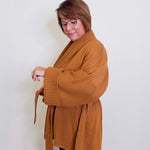 Woman wearing a brown coat against a white wall