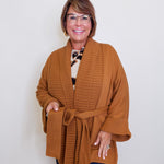 Woman wearing a brown ribbed sweater coat against a white background