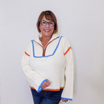 Person wearing a cream sweater with colorful trim against a white background