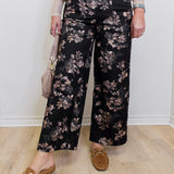 Person wearing black floral pants with a plain background