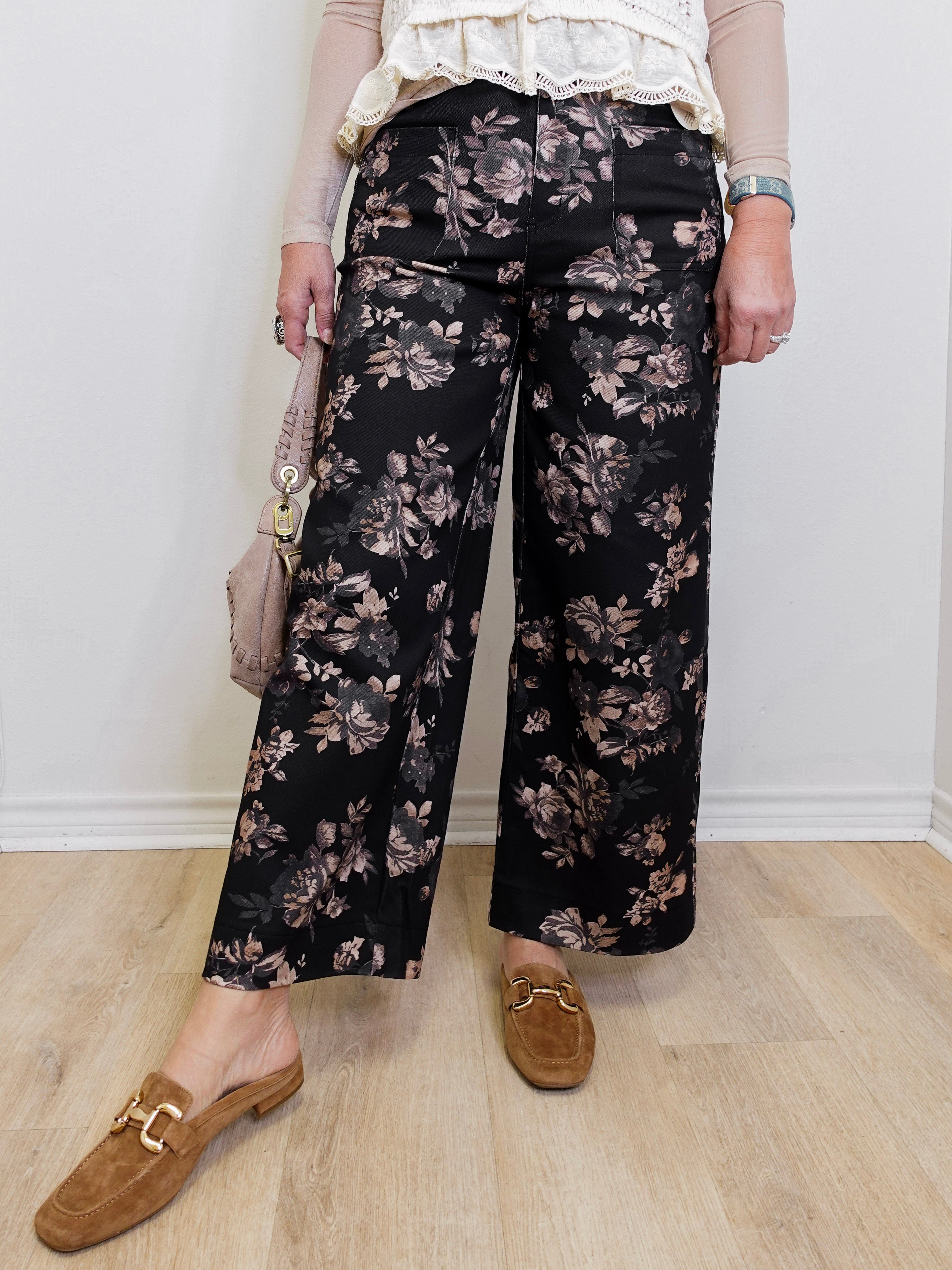 Person wearing black floral pants with a plain background