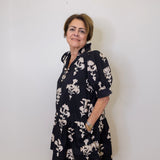 Woman wearing a black floral dress against a white wall