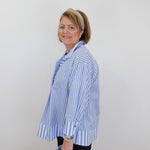Woman wearing a blue and white striped shirt against a plain background