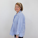 Woman wearing a blue and white striped shirt against a plain background