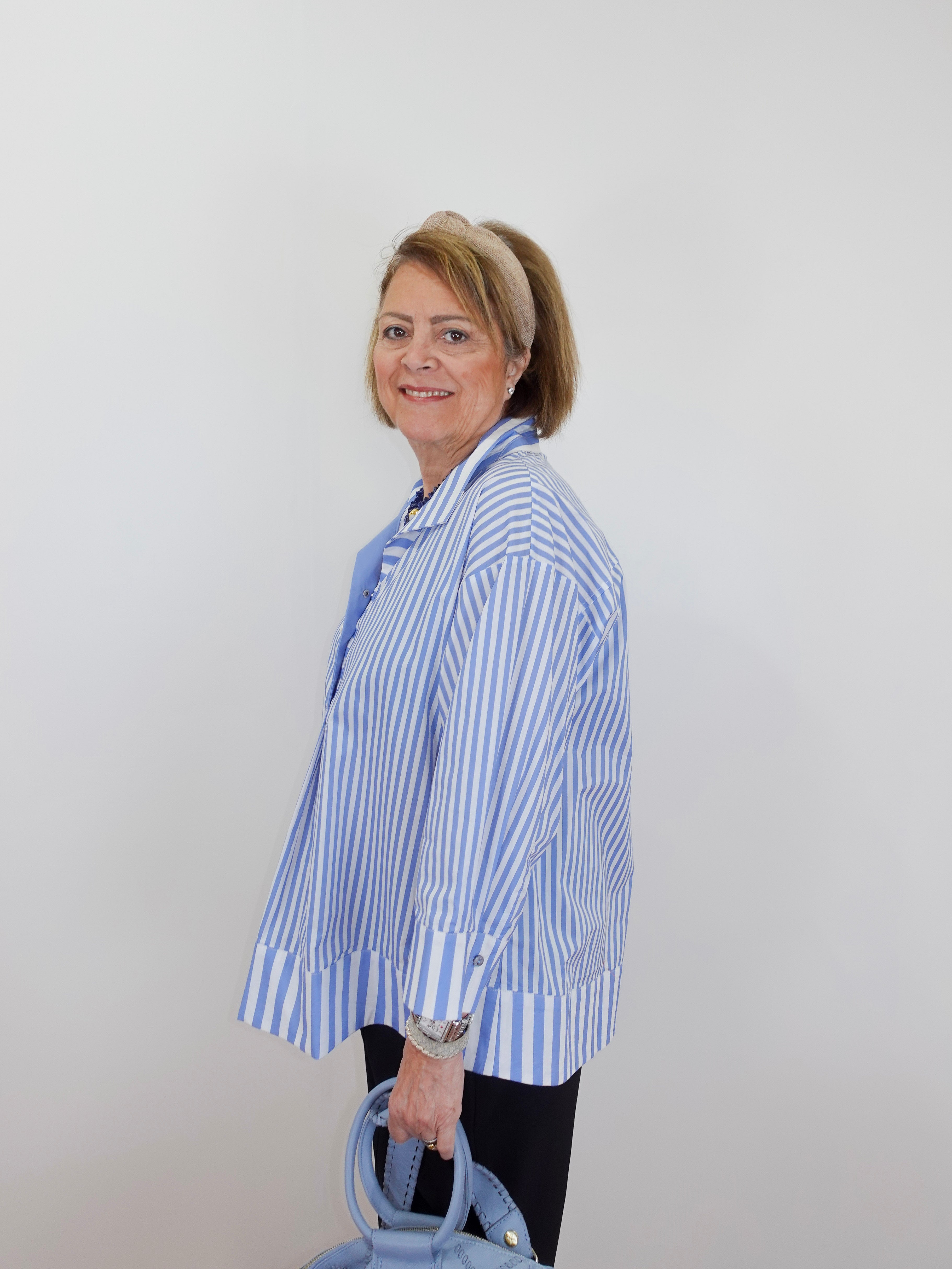 Woman wearing a blue and white striped shirt against a plain background