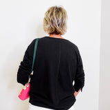 Person wearing a black sweater with a white wall background