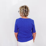 Person wearing a blue shirt and white pants against a white background