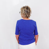 Person wearing a blue shirt and white pants against a white background
