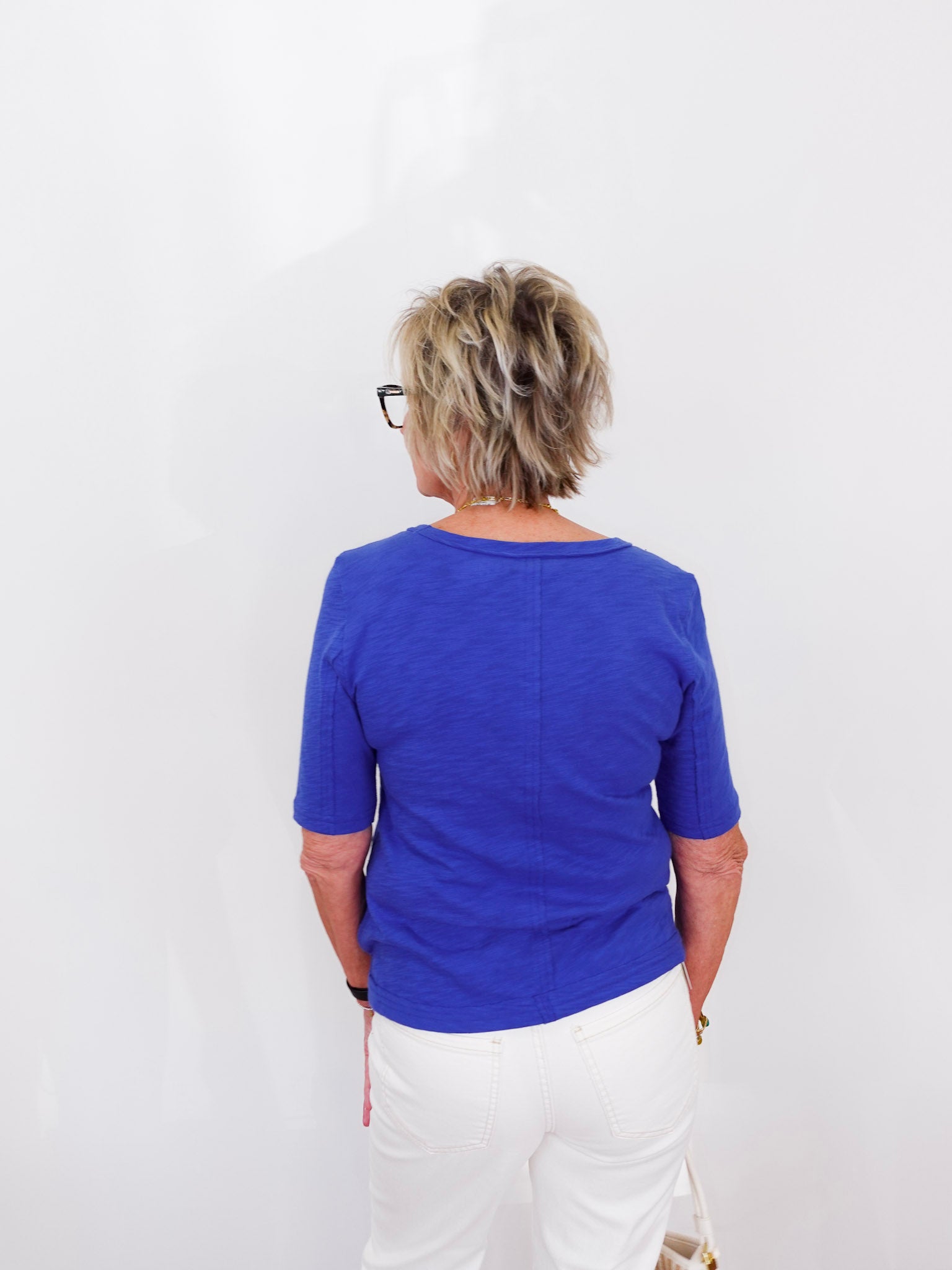 Person wearing a blue shirt and white pants against a white background
