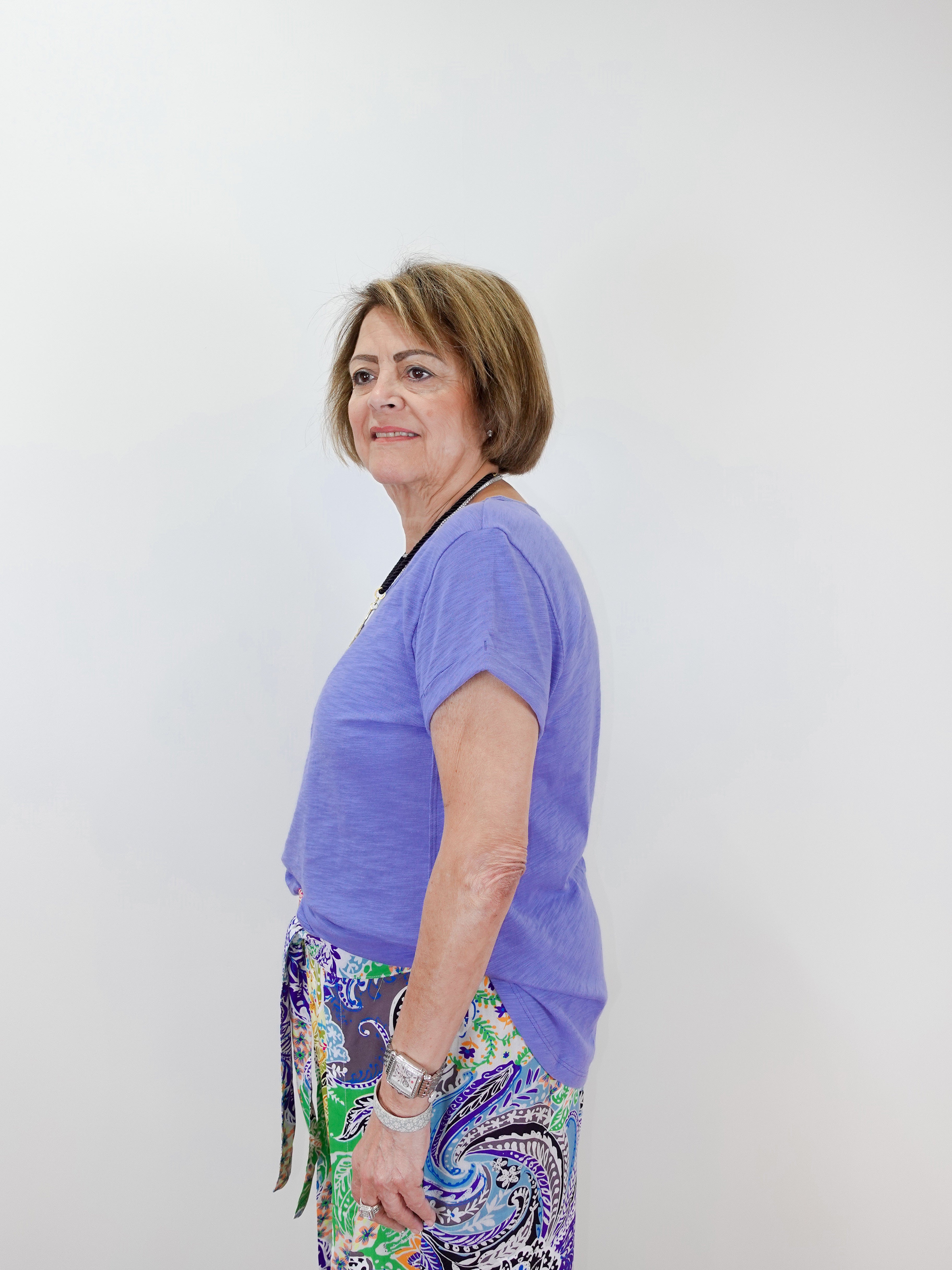Woman wearing a purple shirt and colorful pants against a white background