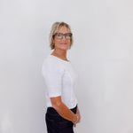 Person wearing a white shirt and black pants against a plain background