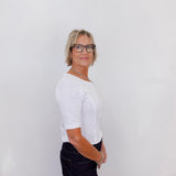 Person wearing a white shirt and black pants against a plain background