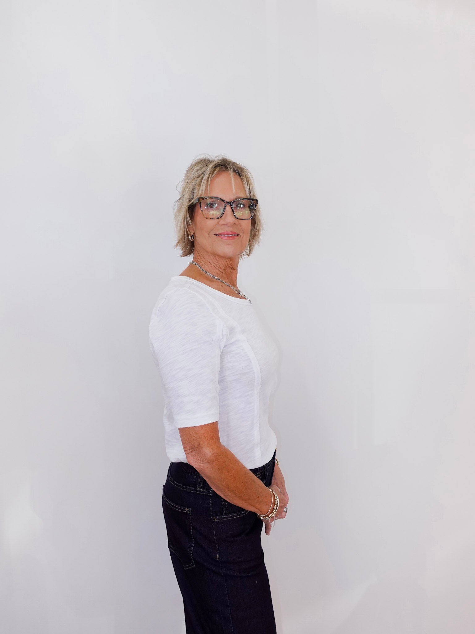 Person wearing a white shirt and black pants against a plain background