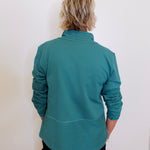 Person wearing a teal long-sleeve shirt against a white background