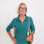 Woman wearing a teal zip-up shirt with a white background