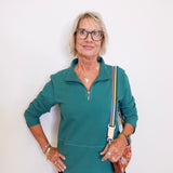 Woman wearing a teal zip-up shirt with a white background