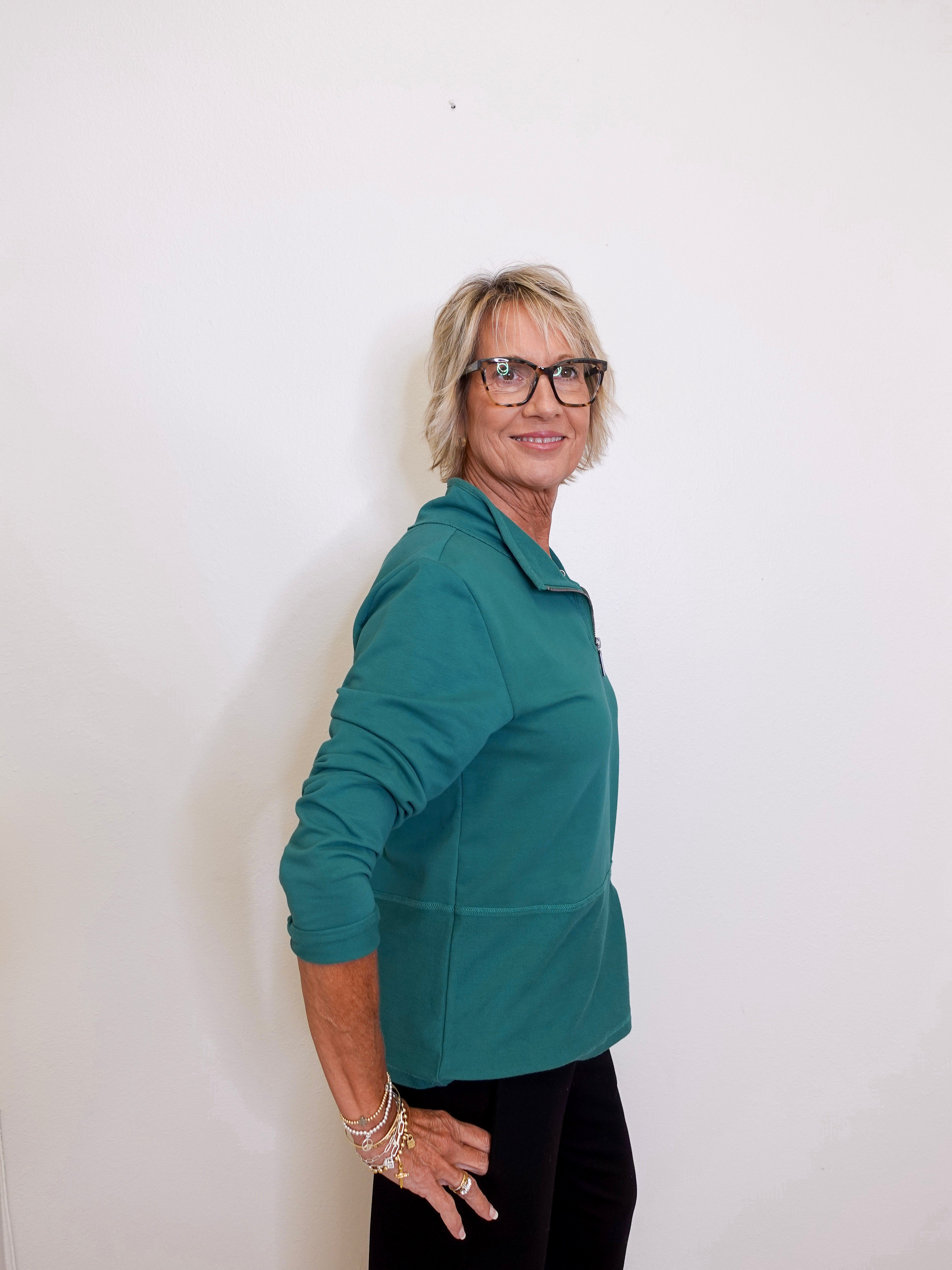 Person wearing a teal jacket against a white background
