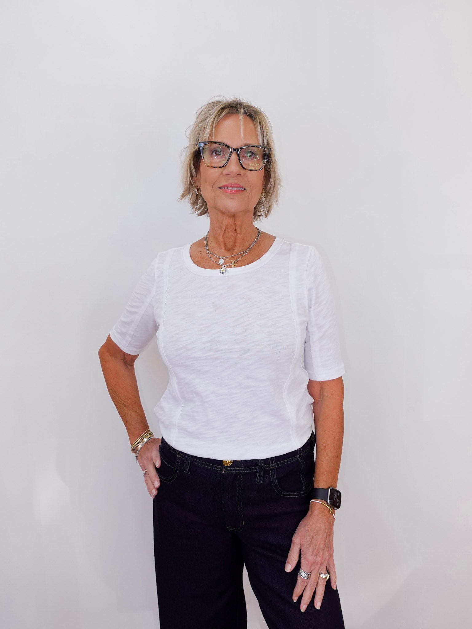 Woman wearing a white shirt and black pants against a plain background